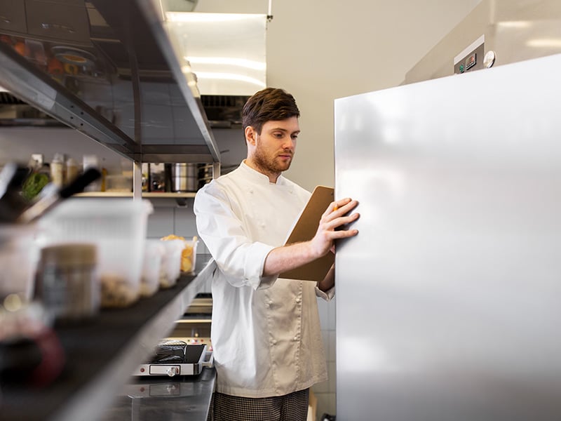 chef with clipboard doing inventory at kitchen